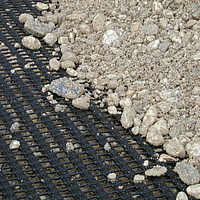 Close-up of a Fortrac Geogrid covered with gravel, ideal for stable soil reinforcement