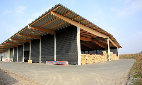 Gran almacén con fachada abierta y tejado voladizo. El lado largo está cerrado por seis frentes grises plegables