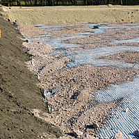 Geomalla Basetrac Grid en una obra, sobre la que ya se ha esparcido arena o grava en algunos lugares.