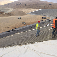 Trabajadores de la construcción colocan y rellenan la estera de hormigón de punto filtrante Incomat