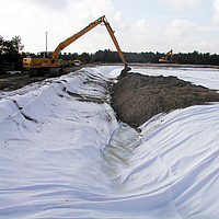 Una excavadora esparce tierra sobre el geocompuesto Basetrac® Duo