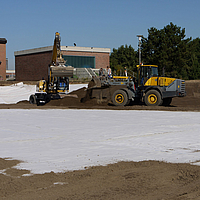 Bulldozer y excavadora esparcen tierra sobre las esteras de bentonita Tektoseal® Clay colocadas