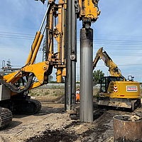 Excavadora llena una columna revestida de Ringtrac® con ayuda de una tolva