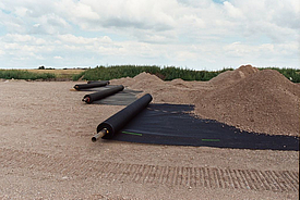 Despliegue de rollos de geomalla Fortrac MDT para el refuerzo de suelos resistentes a los álcalis, aptos para valores extremos de pH y ligantes hidráulicos.